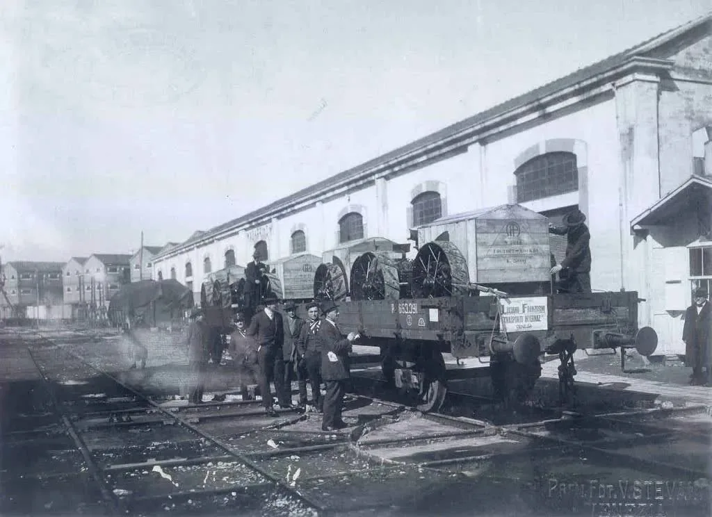 Fotografia storica in bianco e nero di un carro carico di merci con operatori vicino alla ferrovia